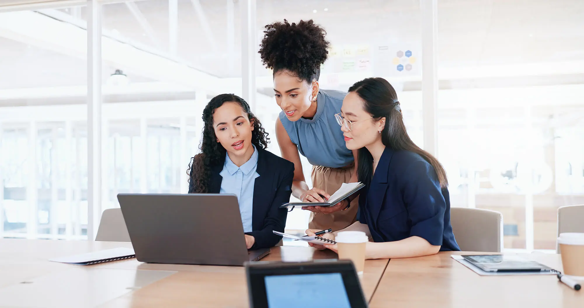 Three people at a conference desk around a laptop